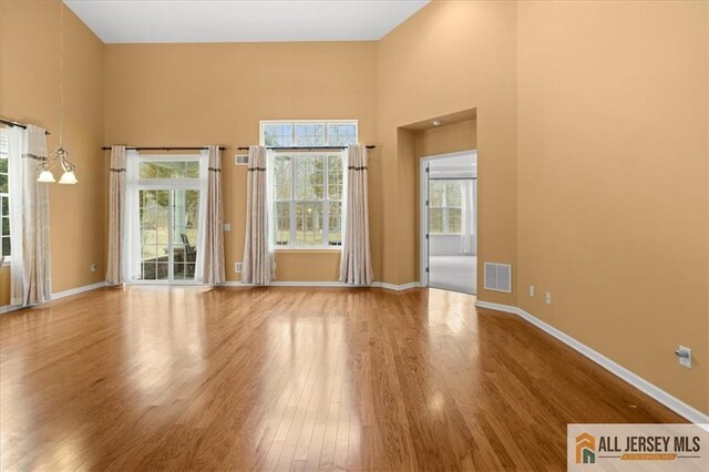 empty room with hardwood / wood-style flooring and a towering ceiling