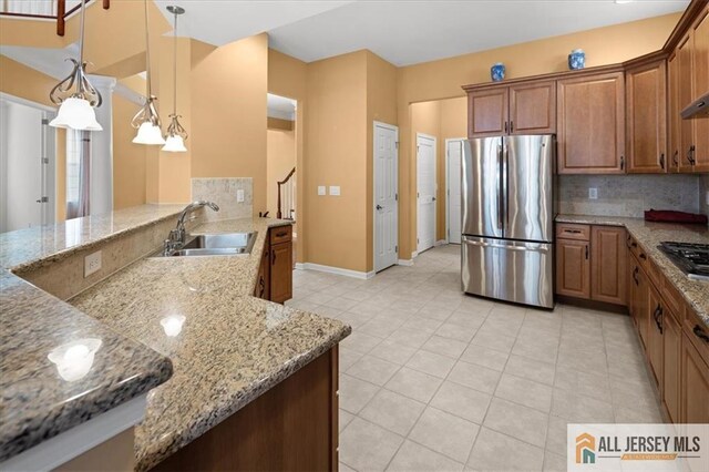 kitchen with decorative light fixtures, sink, light stone counters, kitchen peninsula, and stainless steel appliances