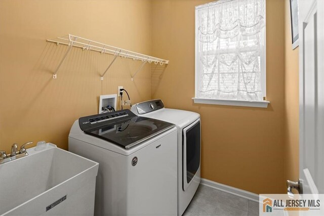 laundry room with sink, light tile patterned floors, and washer and dryer