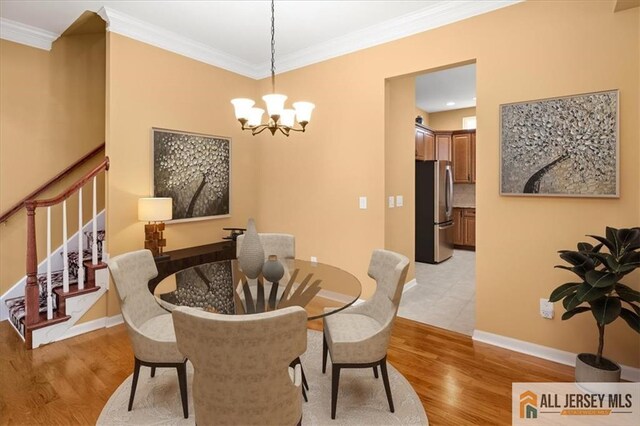 dining room with a notable chandelier, light hardwood / wood-style flooring, and ornamental molding