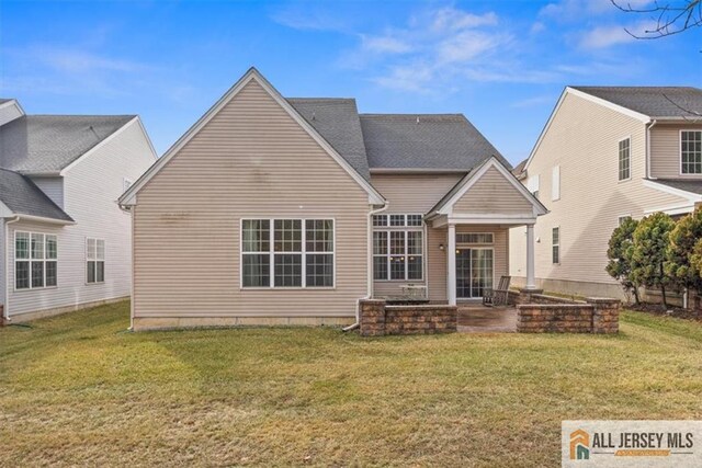 back of property with a yard and a patio