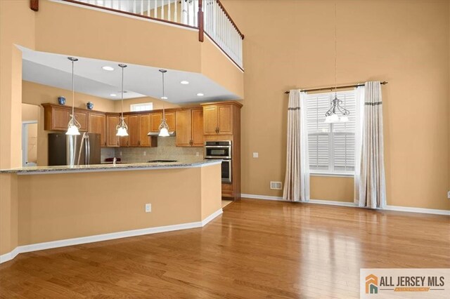 kitchen featuring hanging light fixtures, appliances with stainless steel finishes, and light wood-type flooring