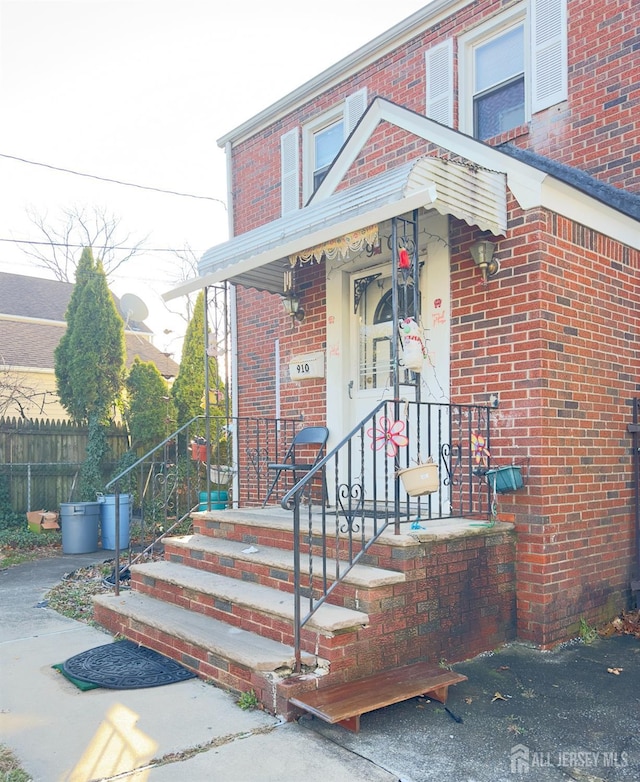 property entrance with brick siding and fence