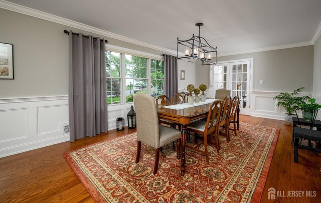 7 Manor Ct, Old Bridge, NJ 08857 - dining space featuring a chandelier, ornamental molding, a wainscoted wall, wood finished floors, and a decorative wall