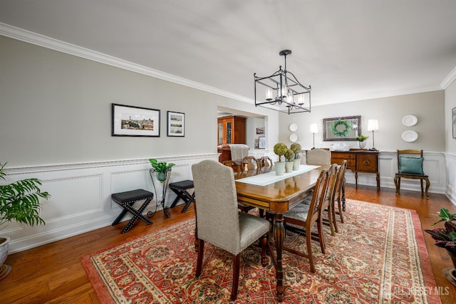 7 Manor Ct, Old Bridge, NJ 08857 - dining space featuring crown molding, a chandelier, wood finished floors, a wainscoted wall, and a decorative wall