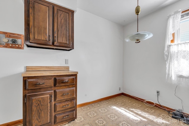 unfurnished dining area featuring light floors and baseboards