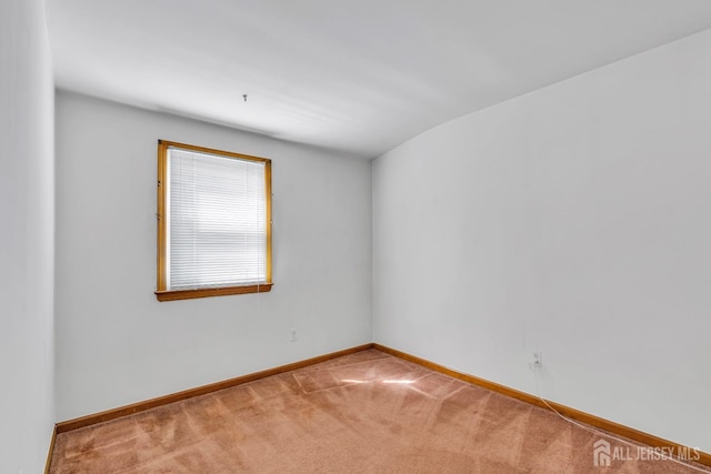 spare room featuring carpet flooring and baseboards