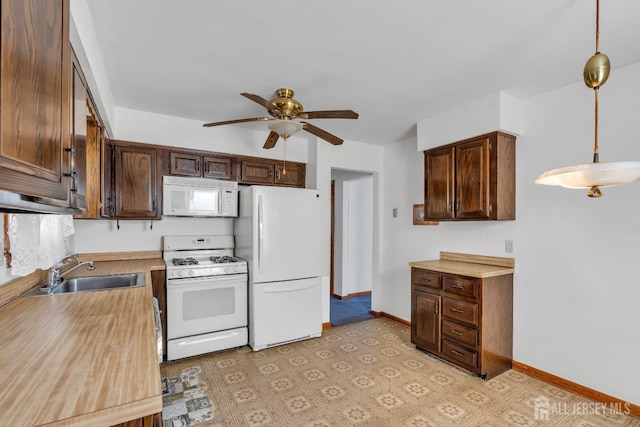 kitchen with white appliances, a sink, a ceiling fan, light countertops, and pendant lighting