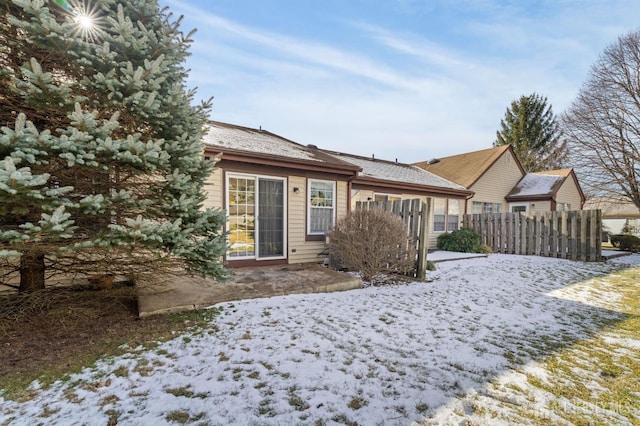 snow covered rear of property with fence