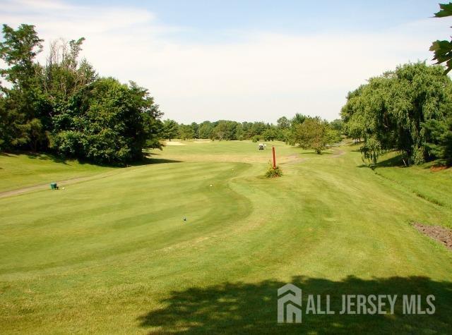 surrounding community with view of golf course and a yard