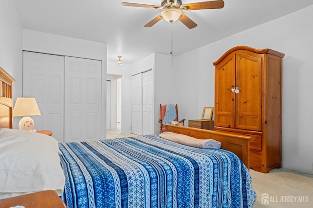 bedroom featuring a ceiling fan, light colored carpet, and multiple closets