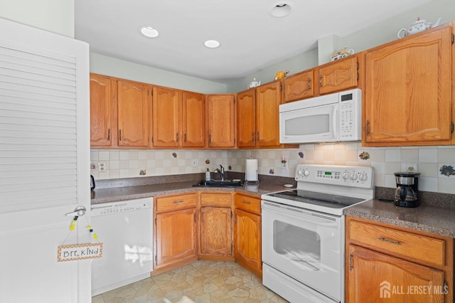 kitchen with white appliances, decorative backsplash, brown cabinetry, dark countertops, and a sink