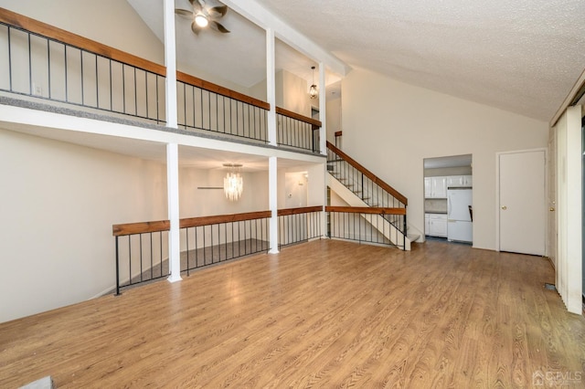 unfurnished living room with wood-type flooring, a textured ceiling, ceiling fan, and high vaulted ceiling