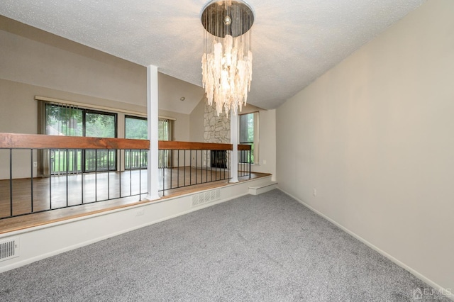 carpeted empty room with a multi sided fireplace, lofted ceiling, an inviting chandelier, and a textured ceiling