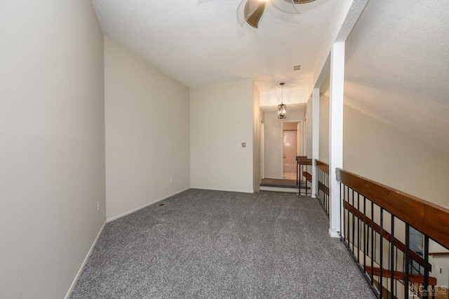 carpeted spare room with ceiling fan, vaulted ceiling, and a textured ceiling