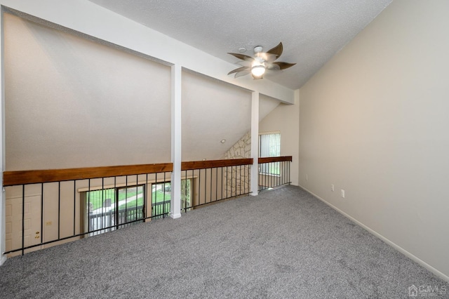 empty room with lofted ceiling, a textured ceiling, ceiling fan, and carpet