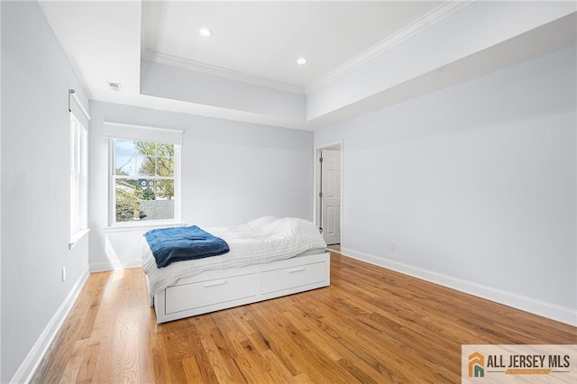 bedroom with ornamental molding, light wood-type flooring, baseboards, a raised ceiling, and recessed lighting