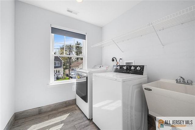 clothes washing area with washing machine and clothes dryer, light wood-style floors, and baseboards