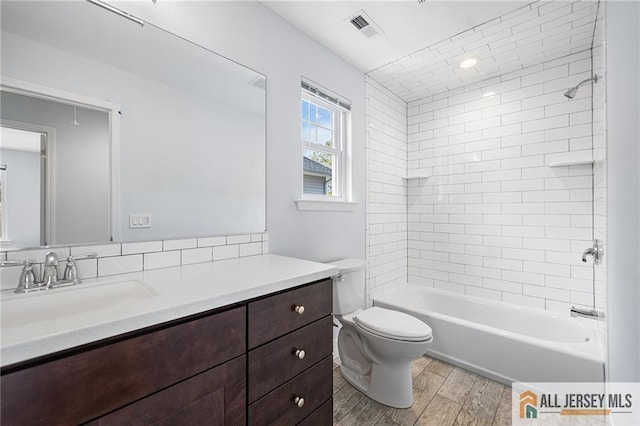 bathroom with wood finished floors, toilet, vanity, and shower / washtub combination