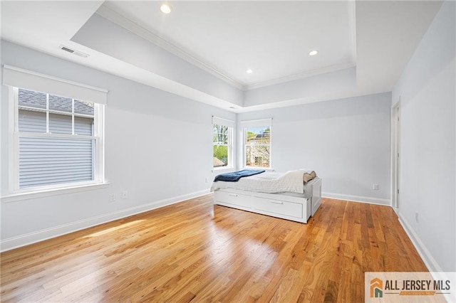 bedroom with a raised ceiling, crown molding, light wood-style floors, baseboards, and recessed lighting