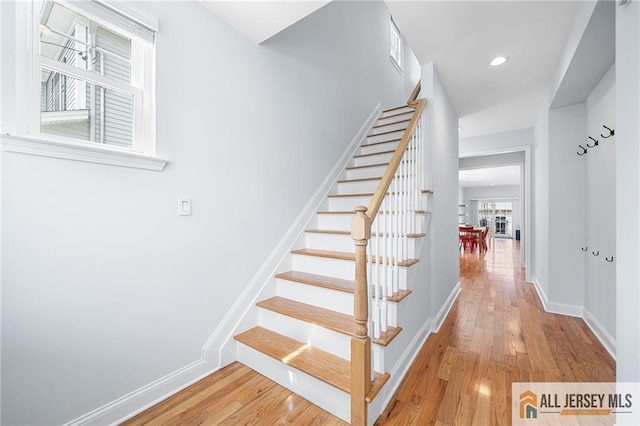 staircase with wood finished floors, baseboards, and recessed lighting