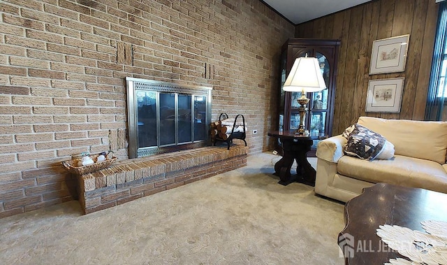 unfurnished living room with brick wall, vaulted ceiling, wood walls, carpet floors, and a brick fireplace