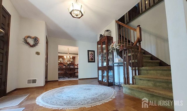 tiled foyer entrance featuring visible vents, a notable chandelier, stairway, and baseboards