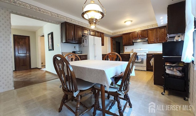 dining space featuring light floors, baseboards, and wallpapered walls