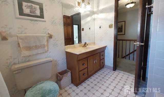 bathroom with vanity, toilet, and wallpapered walls