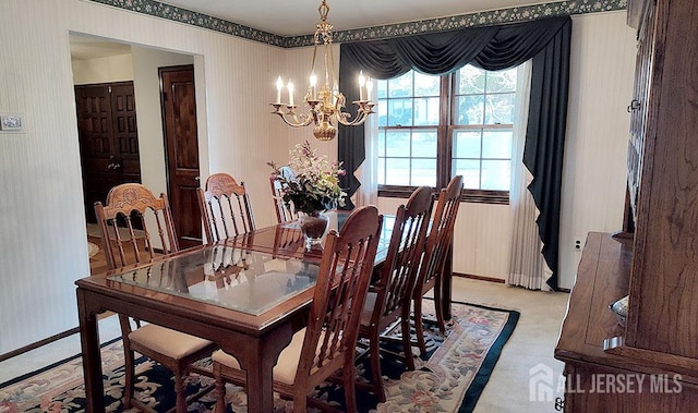 dining area with a chandelier, baseboards, and wallpapered walls