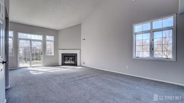 52-C Rutland Ln, Monroe, NJ 08831 - unfurnished living room featuring carpet floors, a textured ceiling, baseboards, a fireplace with flush hearth, and vaulted ceiling