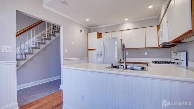 52-C Rutland Ln, Monroe, NJ 08831 - kitchen with white appliances, a peninsula, light countertops, a sink, and crown molding