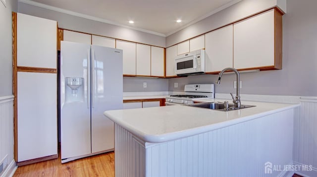 52-C Rutland Ln, Monroe, NJ 08831 - kitchen with white appliances, a sink, a peninsula, light countertops, and ornamental molding