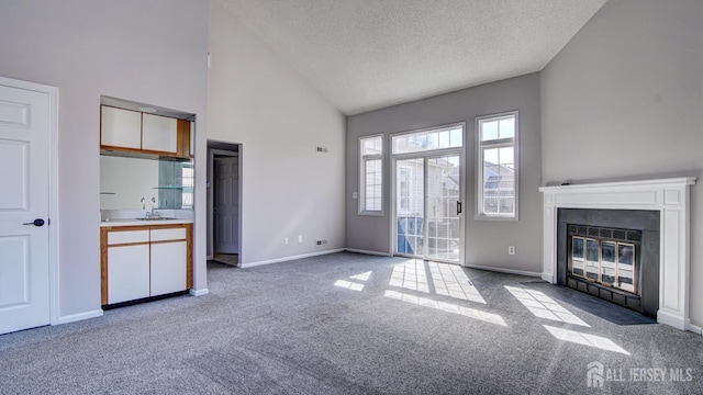 52-C Rutland Ln, Monroe, NJ 08831 - unfurnished living room with high vaulted ceiling, carpet floors, a textured ceiling, a fireplace with flush hearth, and a sink