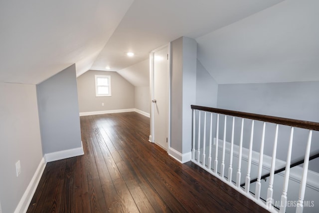 bonus room featuring lofted ceiling, baseboards, and dark wood-type flooring