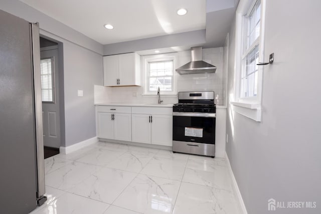 kitchen with tasteful backsplash, wall chimney exhaust hood, appliances with stainless steel finishes, marble finish floor, and a sink