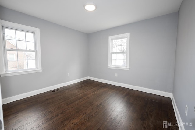 unfurnished room featuring dark wood-type flooring and a wealth of natural light