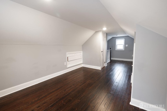 additional living space with dark wood-style flooring, vaulted ceiling, and baseboards