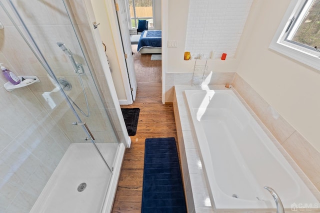 bathroom featuring a healthy amount of sunlight, plus walk in shower, and hardwood / wood-style floors