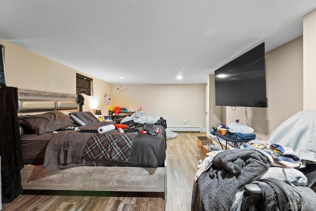 bedroom with wood-type flooring and a baseboard heating unit