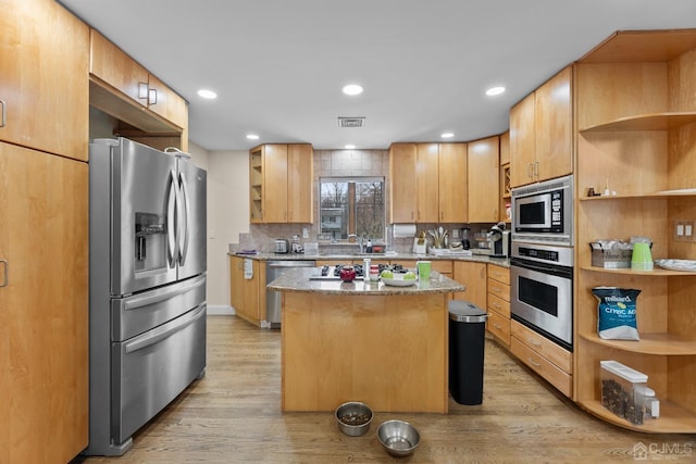 kitchen featuring stainless steel appliances, a center island, backsplash, and light hardwood / wood-style floors