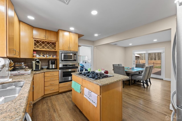 kitchen featuring dark hardwood / wood-style flooring, decorative backsplash, a kitchen island, and appliances with stainless steel finishes