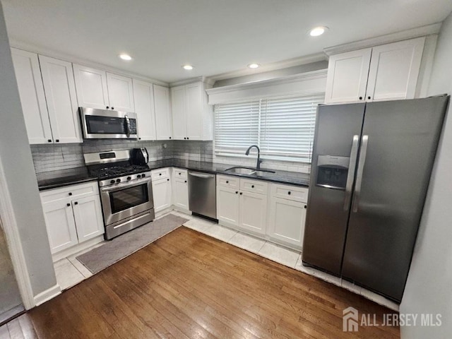 45 E Oak St, Carteret, NJ 07008 - kitchen featuring appliances with stainless steel finishes, dark countertops, white cabinets, light wood-type flooring, and recessed lighting