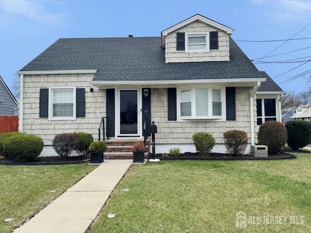 cape cod-style house featuring roof with shingles and a front lawn