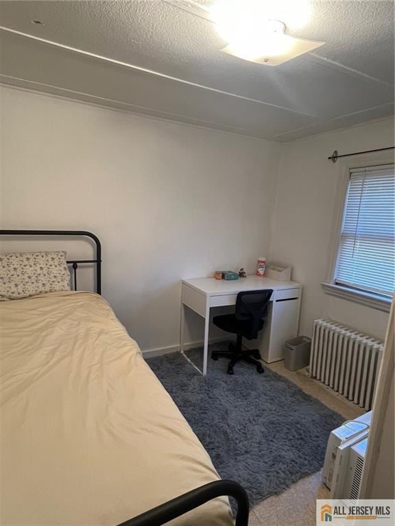 carpeted bedroom featuring a textured ceiling and radiator heating unit