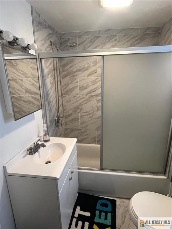 full bathroom with vanity, combined bath / shower with glass door, and toilet