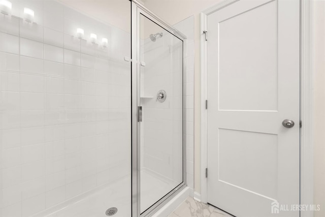 bathroom with a shower stall and marble finish floor