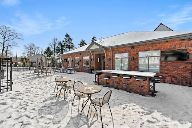 snow covered patio with fence and outdoor dry bar
