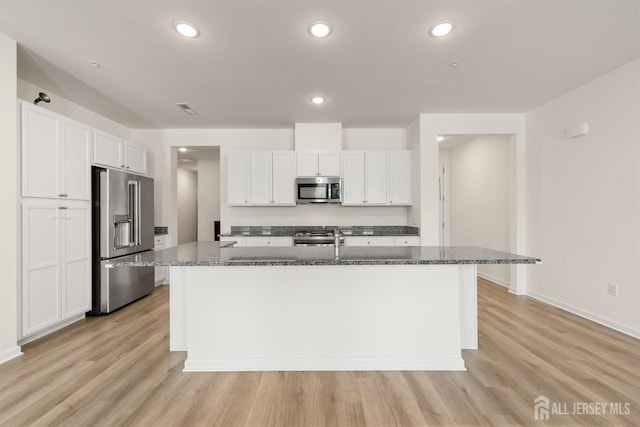kitchen with light wood-style flooring, a kitchen island with sink, stainless steel appliances, and white cabinetry