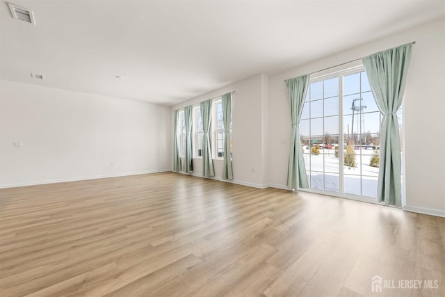 empty room with baseboards, visible vents, and light wood-type flooring